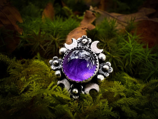 A rich purple, round cut amethyst ring in sterling silver with flowers and crescent moons. Polished and oxidised. Handmade by Jen Smith, Silver Labyrinth Jewelry 