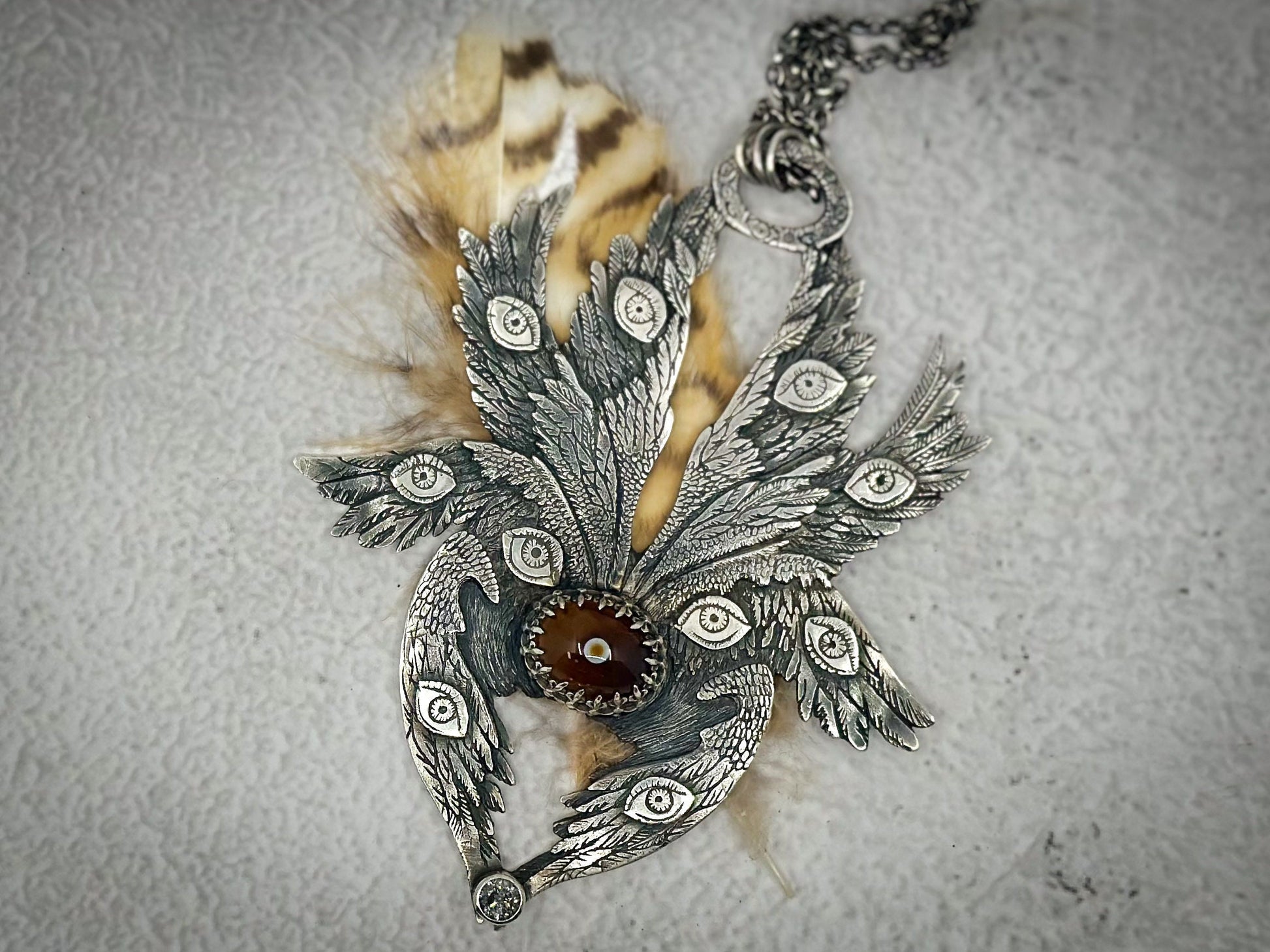 Handmade Sterling Silver Biblically Accurate Angel Pendant with Eye Agate and Salt and Pepper Diamond
This detailed sterling silver pendant features eight wings, intricate eyes, and feathers. Designed and handmade by Jen Smith, it includes a chain and is available in other sizes.