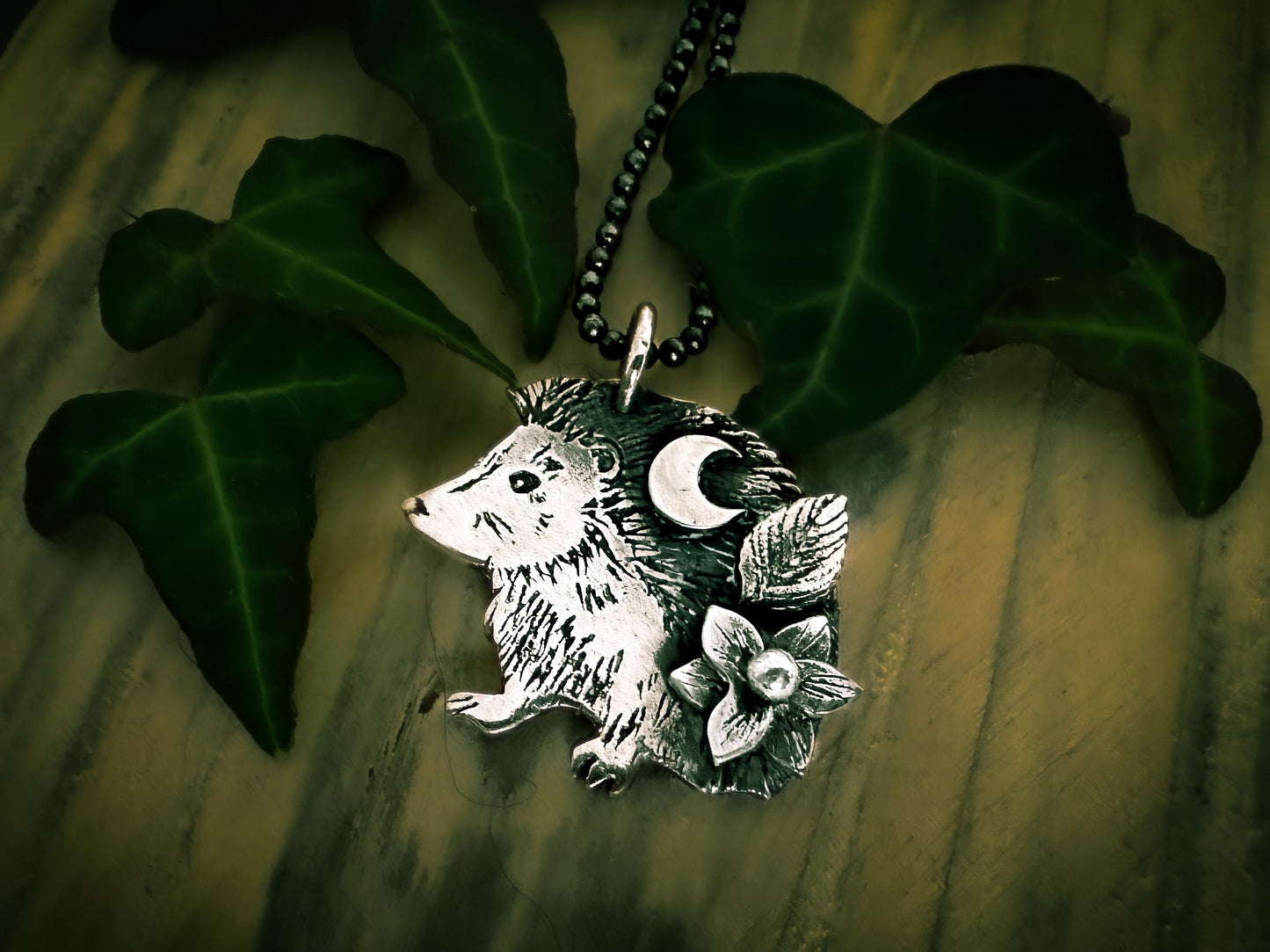 View from below: Cute hedgehog pendant in sterling silver with flower, leaf and moon. By SILVER LABYRINTH JEWELRY