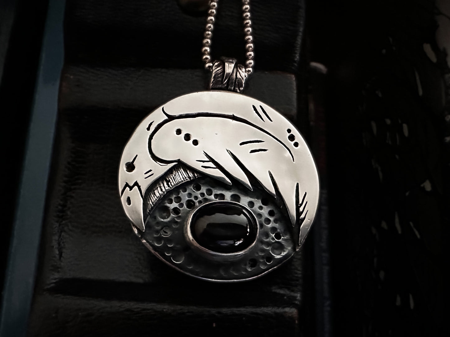 A silver Stylised Raven above a black star diopside cabochon.