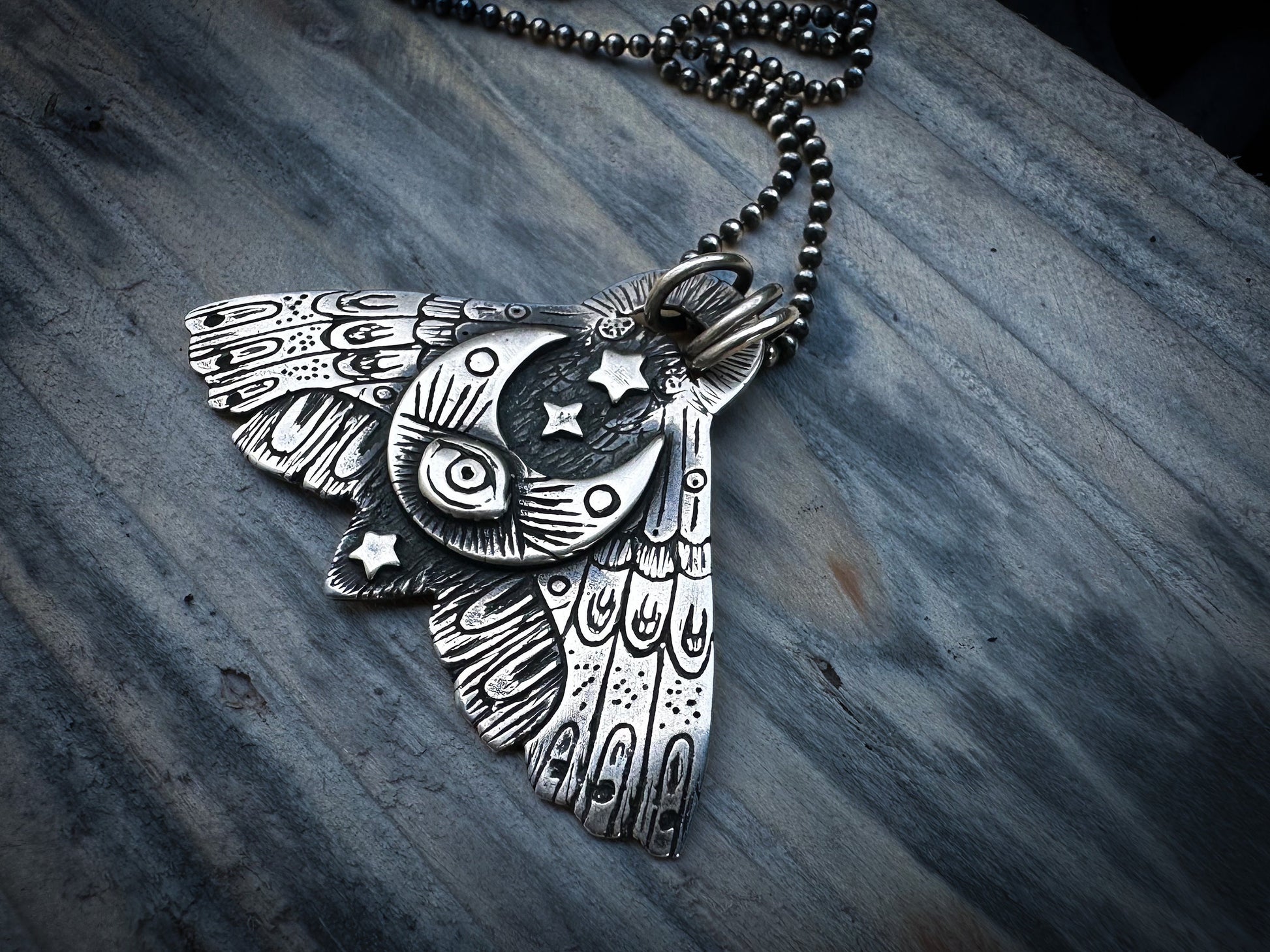 Silver Moth necklace embodying themes of decay, renewal, and the liminal space between light and shadow.