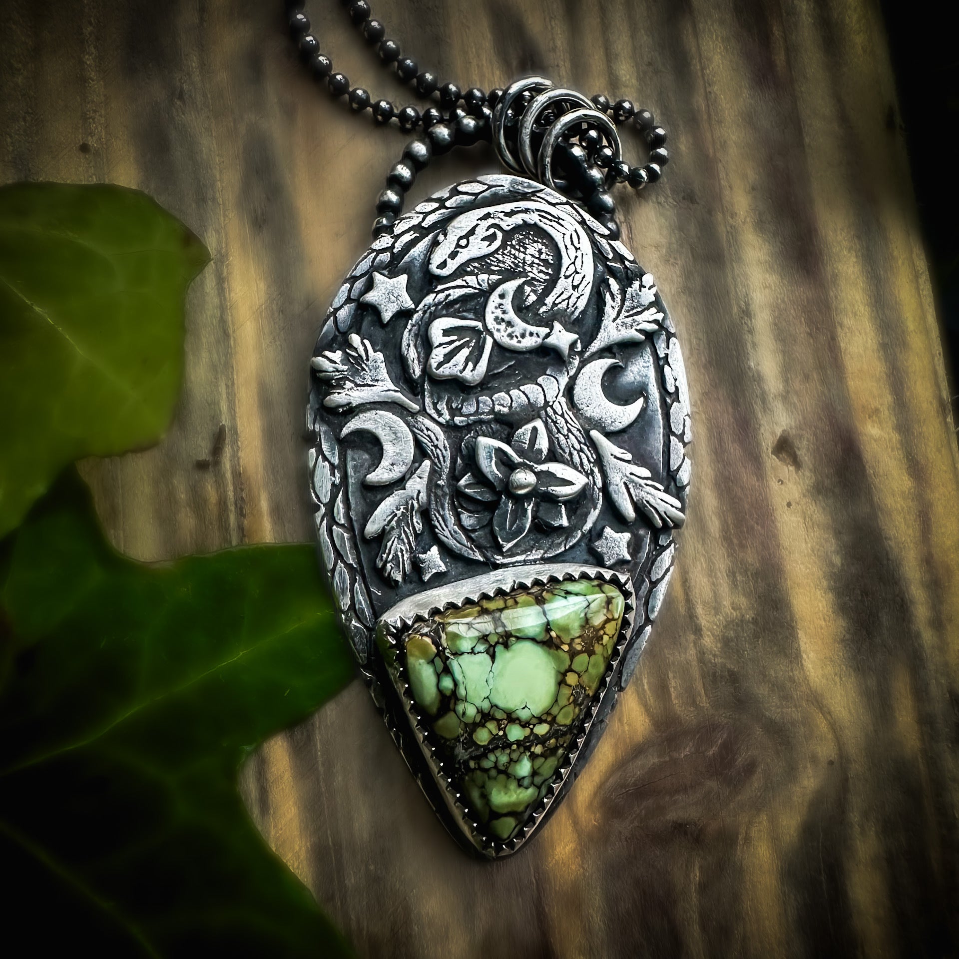 Silver snake totem pendant featuring textured leaves, a delicate flower, and a rare Damele variscite gemstone. Handmade in sterling silver by Silver Labyrinth Jewelry 