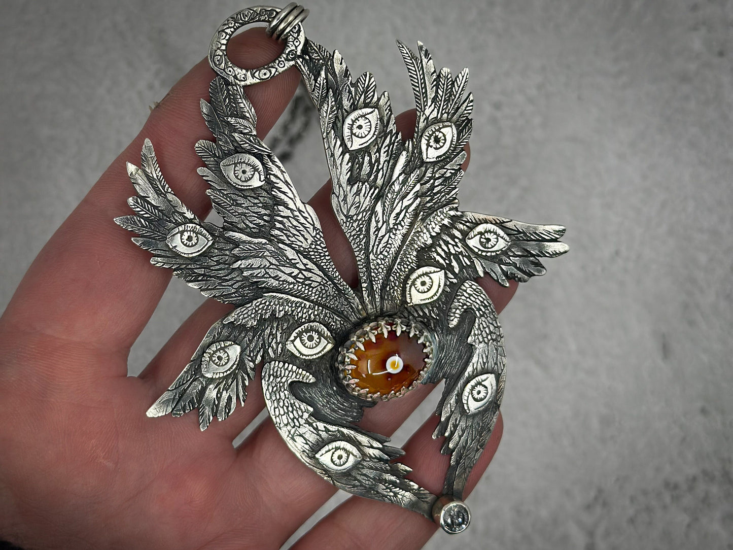 Sterling Silver Occult Biblically Accurate Angel Pendant with Eye Agate and Salt and Pepper Diamond. 
This detailed sterling silver pendant features eight wings, intricate eyes, and feathers. Designed and handmade by Jen Smith, it includes a chain and is available in other sizes.