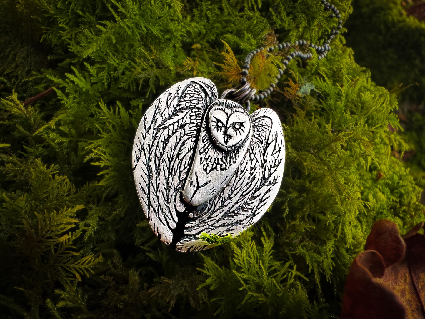 Side view of Owl talisman. The barn owl’s wings are detailed with feathers as though in flight. It is rustic in style and handmade in solid silver. By Silver Labyrinth Jewelry 