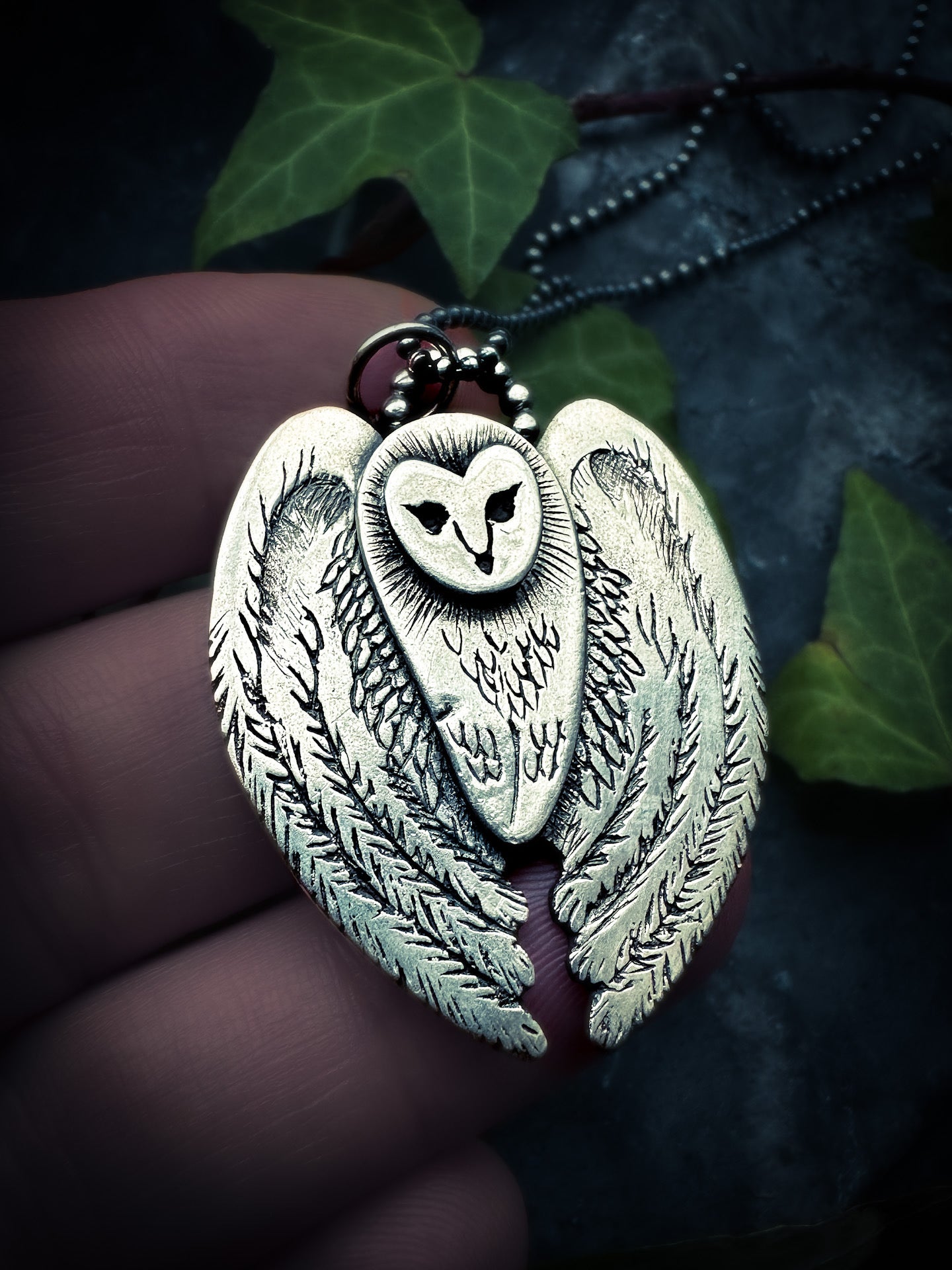 Close-up of a handmade owl pendant showcasing intricate textures and polished finish. Handmade by Silver Labyrinth Jewelry 