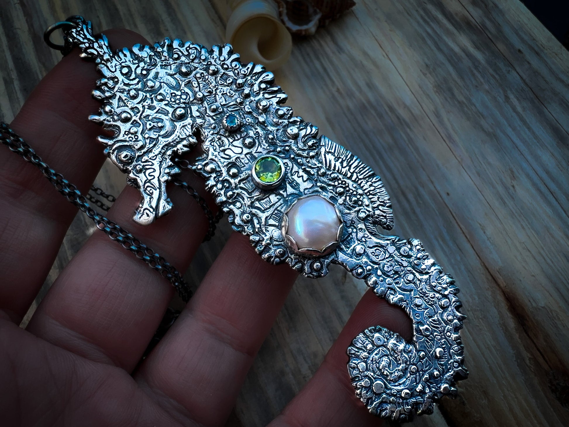 Detailed silver seahorse pendant inspired by the water element, featuring organic textures and vibrant gemstones