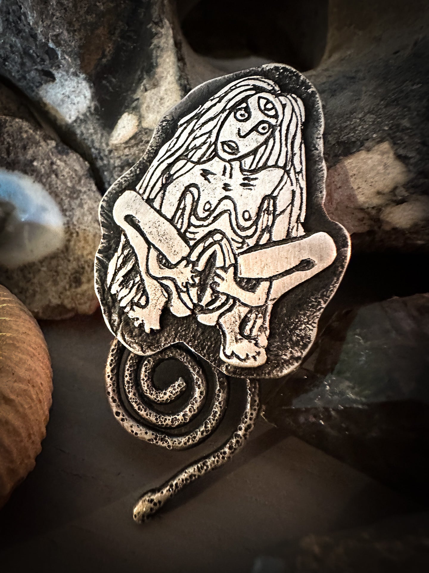 A fearless icon of female empowerment, sheila na gig handmade in sterling silver with coiled spiral snake. By Silver Labyrinth Jewelry.