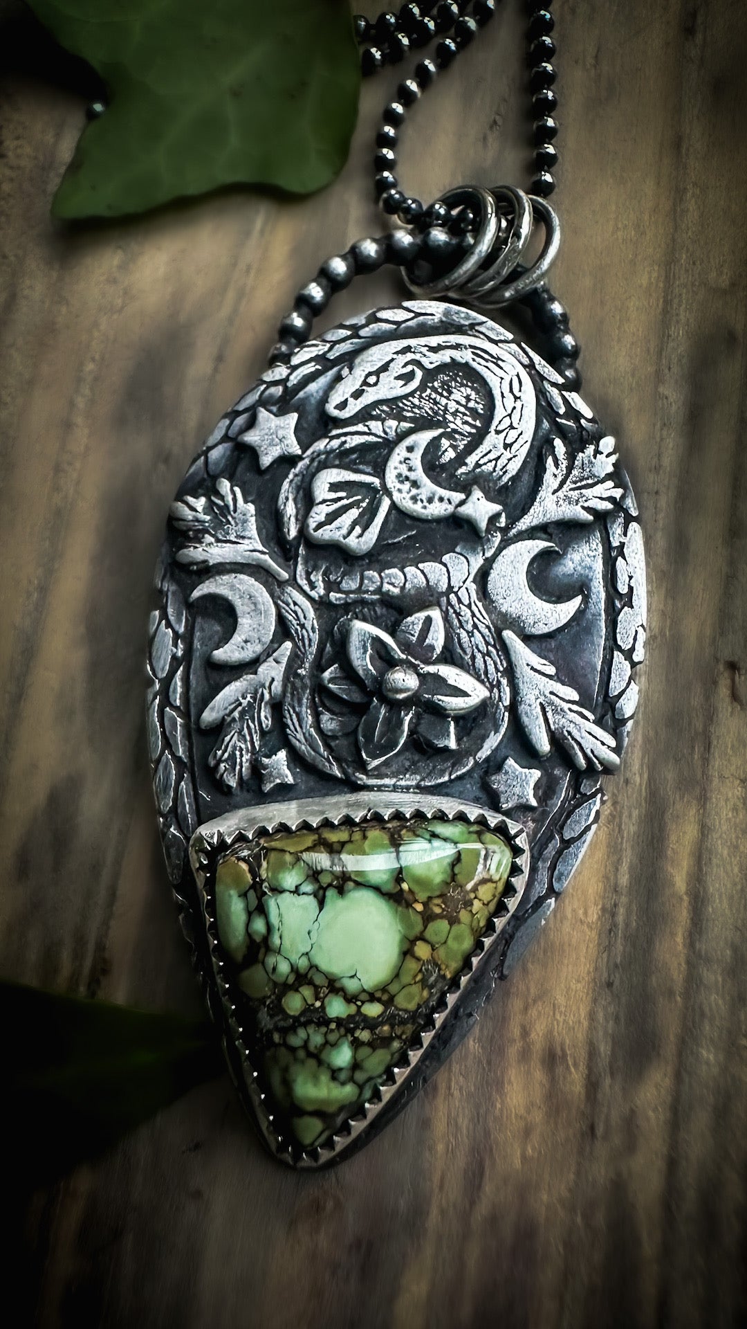 Intricate silver snake pendant with textured leaves, floral details and a moody Damele variscite centerpiece. Handmade by Silver Labyrinth Jewelry