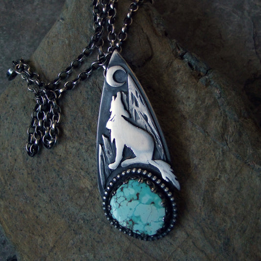 Turquoise wolf pendat, howling at the moon against a mountain landscape. Antiqued with a patina and polished to bring out the details. 