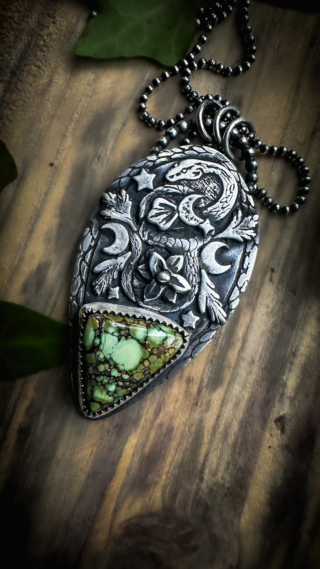 Silver snake pendant symbolizing transformation and renewal, set with a rare variscite stone and leafy accents