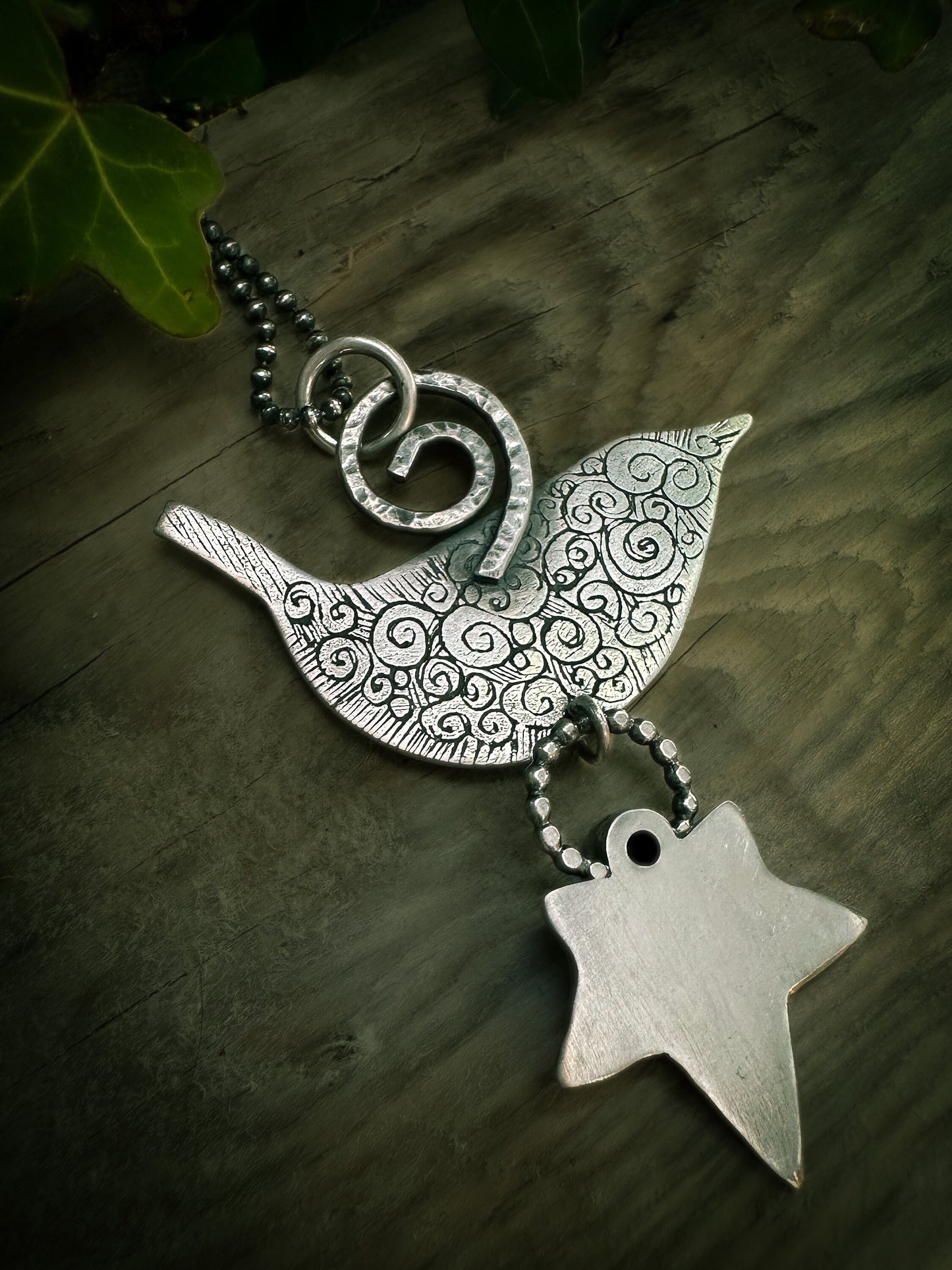 Close-up of handmadeBack view of Druid Bird Wren pendant showing the symbolic spiral design. By Silver Labyrinth Jewelry