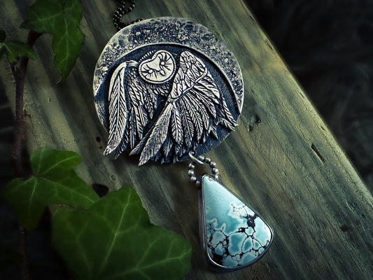 Statement, round Barn Owl pendant with finely detailed wings against a textured and hammered crescent moon. Handmade by Jen Smith in solid sterling silver with a natural lavender Sand Hill Mine turquoise. silverlabyrinthjewelry.com