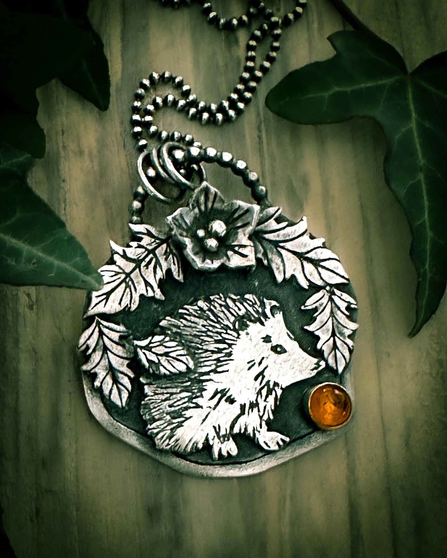 Detailed view of autumn hedgehog pendant, showing the exquisite details. Five silver leaves and a flower, set with amber. By Silver Labyrinth Jewelry